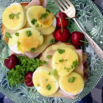 eggs benedict on a green glass plate with a fork