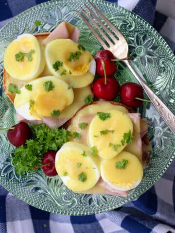 eggs benedict on a green glass plate with a fork