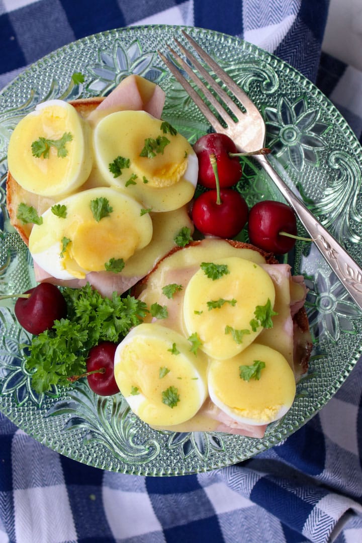 eggs benedict on a green glass plate with a fork