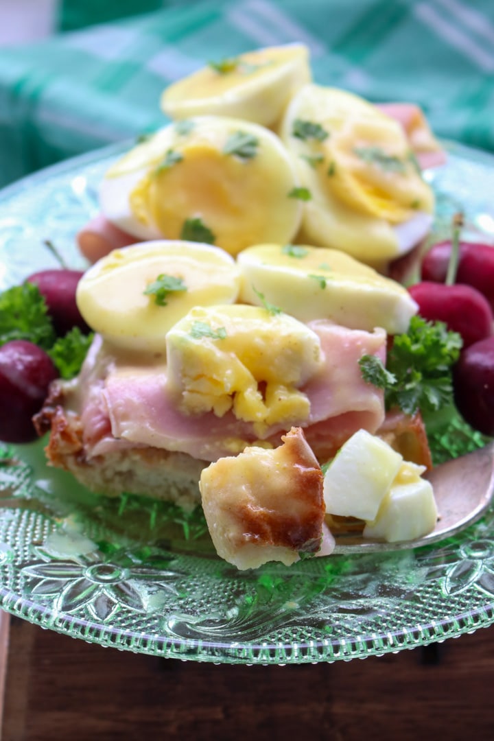 eggs benedict on a green glass plate with a fork