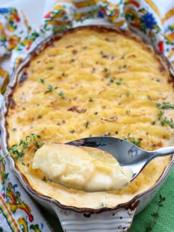 cheesy au gratin potatoes being served with a large spoon