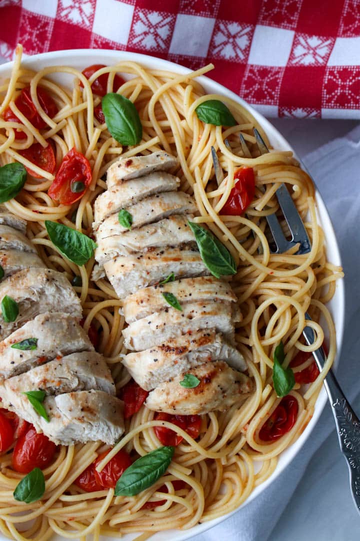 two chicken breasts on a plate of pasta