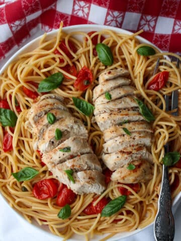 two chicken breasts on a plate of pasta