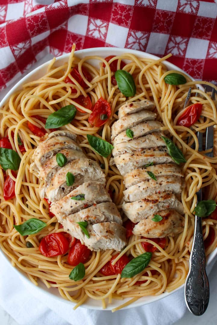 two chicken breasts on a plate of pasta