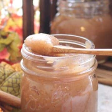 apple butter in a jar with a spoon on top of the jar