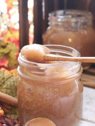 apple butter in a jar with a spoon on top of the jar