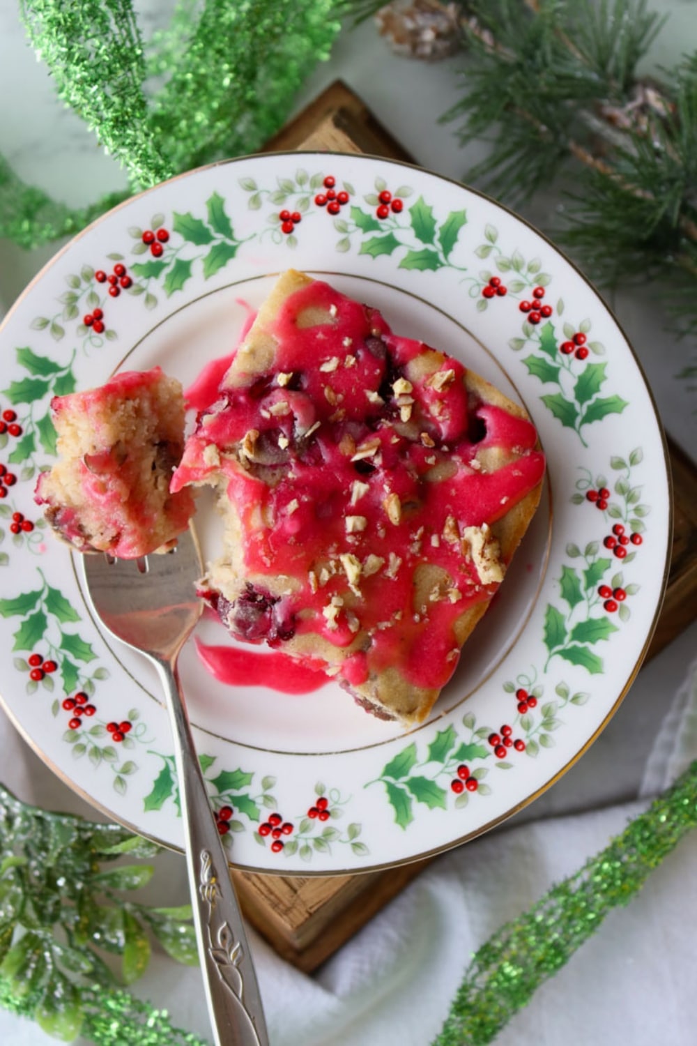 slice of baked cranberry pancake topped with cranberry glaze on a Christmas plate with fork on left side of plate.