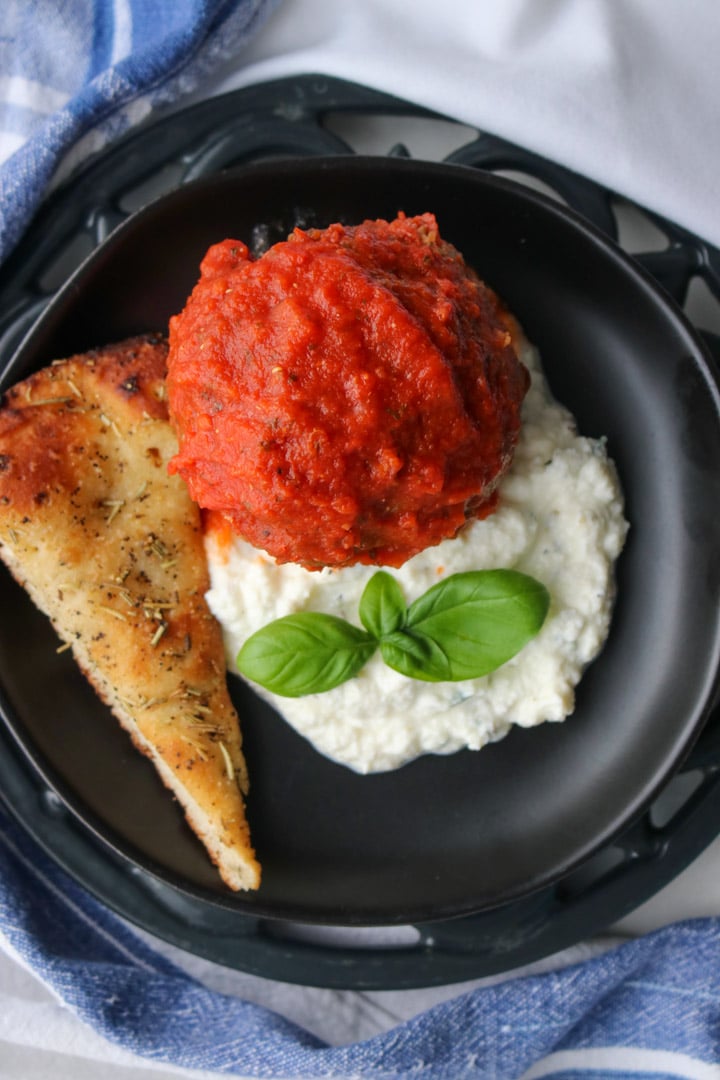 meatball on a plate with herbed ricotta and pizza bread