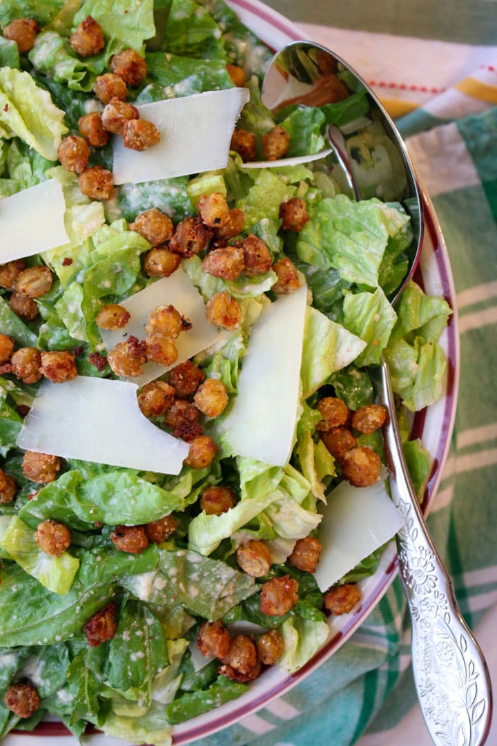 bowl of caesar salad topped with chickpeas and parmesan cheese