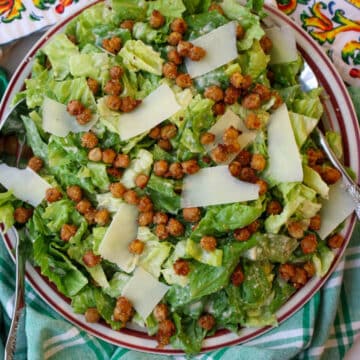 bowl of caesar salad topped with chickpeas and parmesan cheese