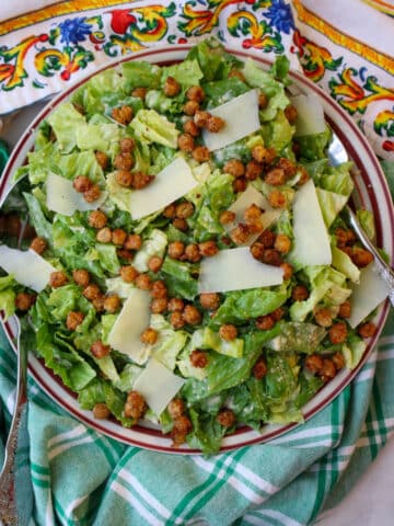 bowl of caesar salad topped with chickpeas and parmesan cheese