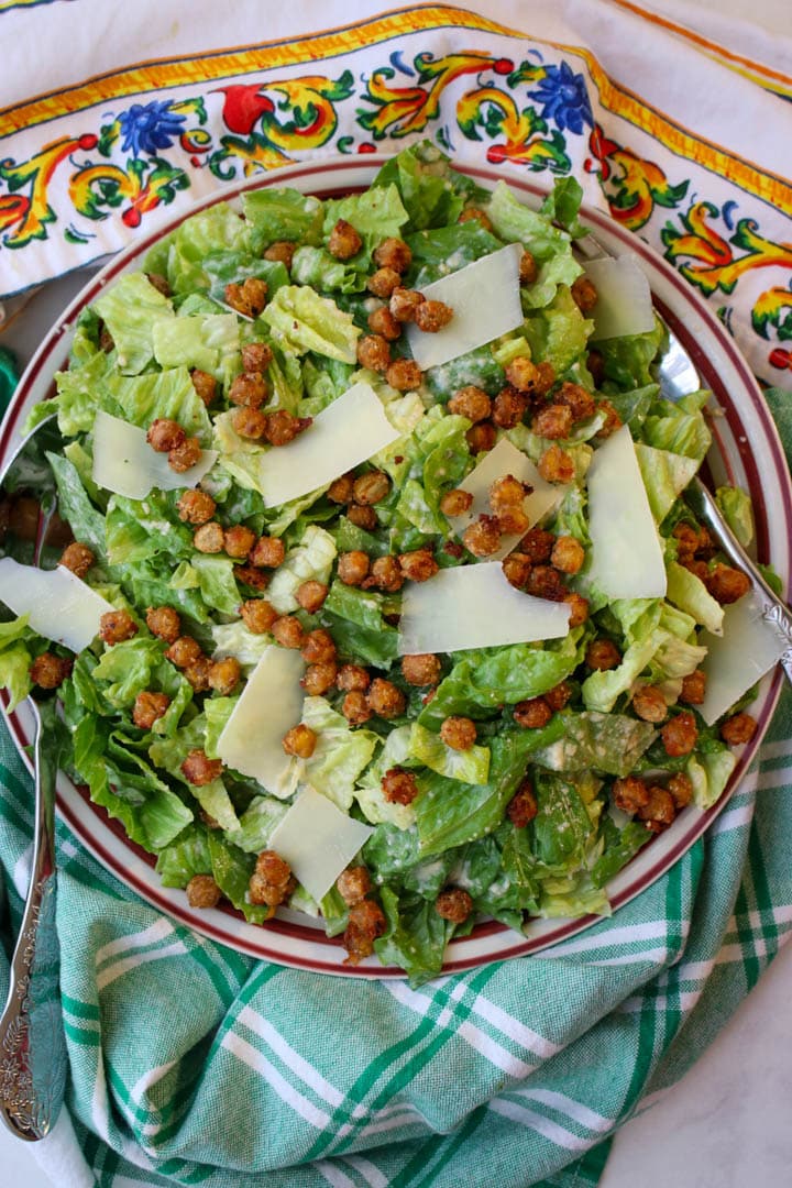 bowl of caesar salad topped with chickpeas and parmesan cheese