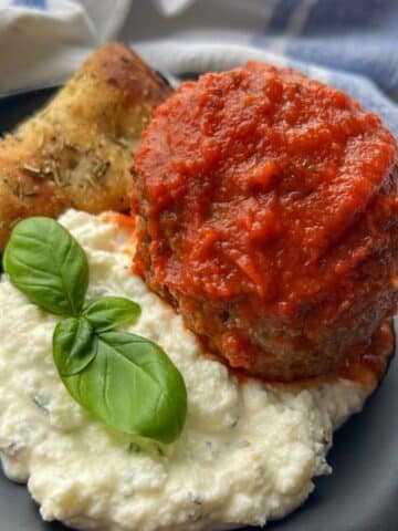 meatball on a plate with herbed ricotta and pizza bread