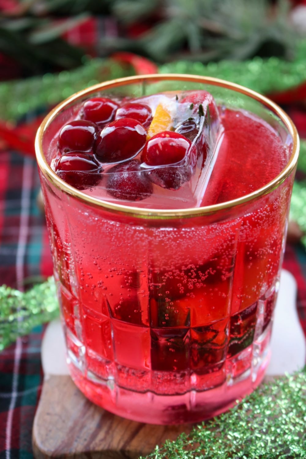 glass rimmed in gold and filled with cranberry juice and fruit filled ice cubes