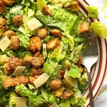 bowl of Crispy Parmesan Potato Caesar Salad with a spoon on the right side