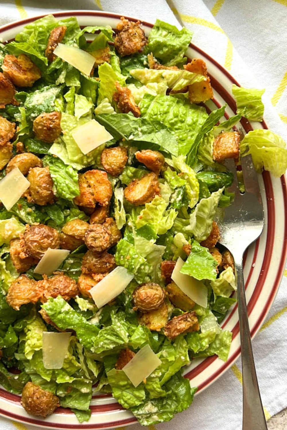 bowl of Crispy Parmesan Potato Caesar Salad with a spoon on the right side