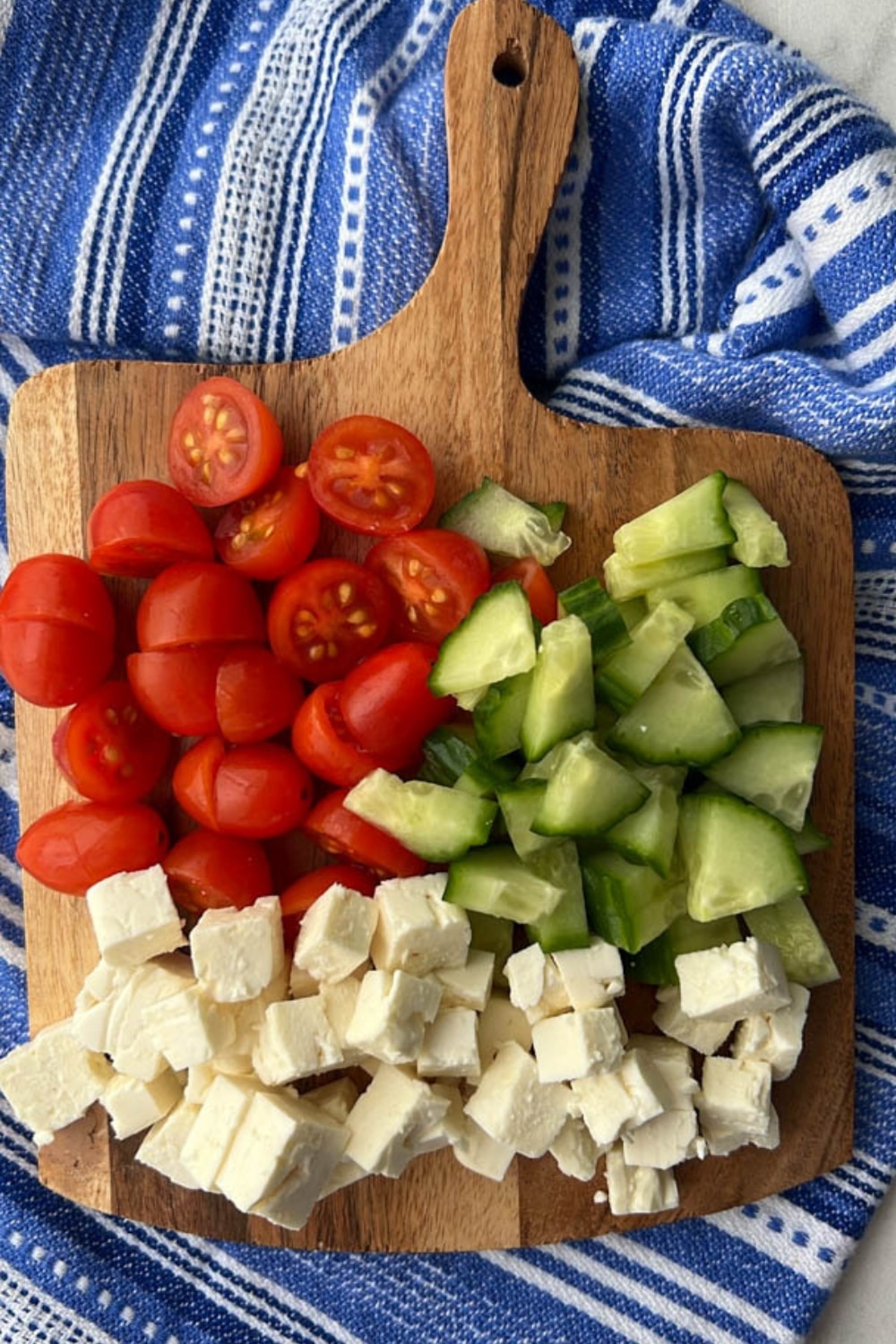 CUTTING BOARD WITH DICED TOMATOES, CUCUMBERS AND FETA CHEESE
