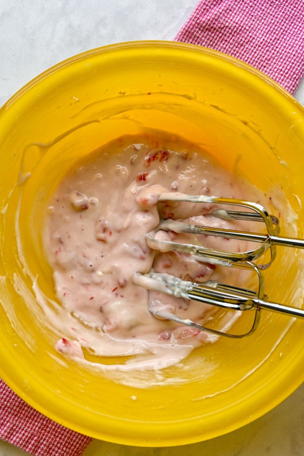 STRAWBERRY CREAM CHEESE FROSTING IN A BOWL WITH BEATERS