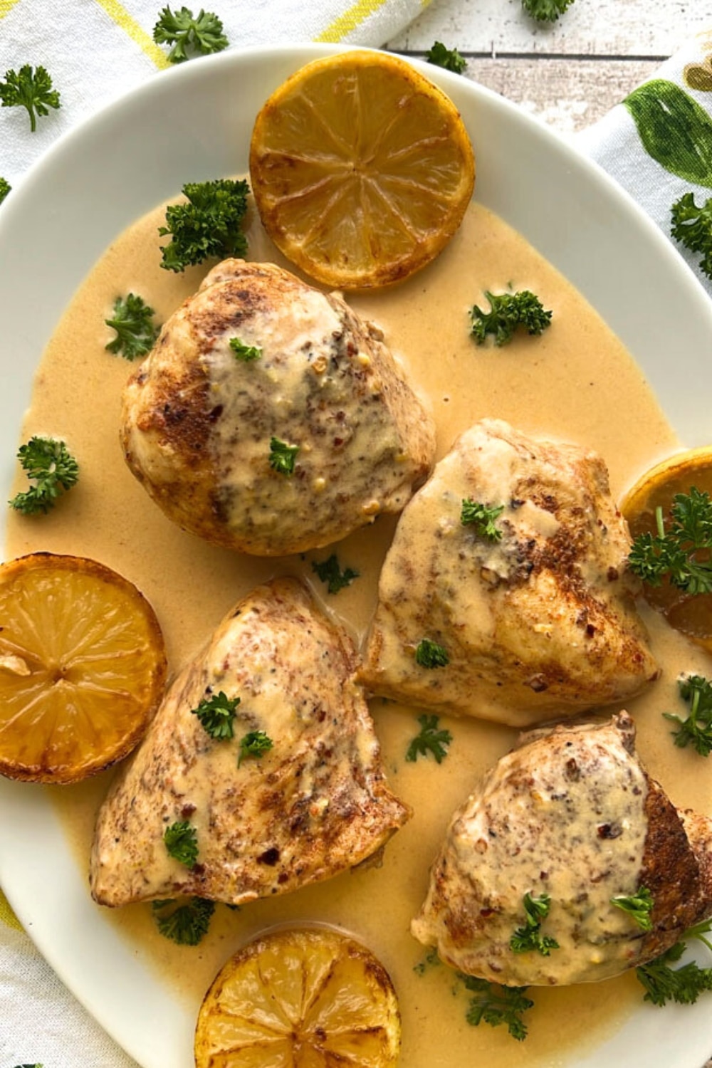 platter of chicken thighs on a parmesan lemon sauce garnished with parsley