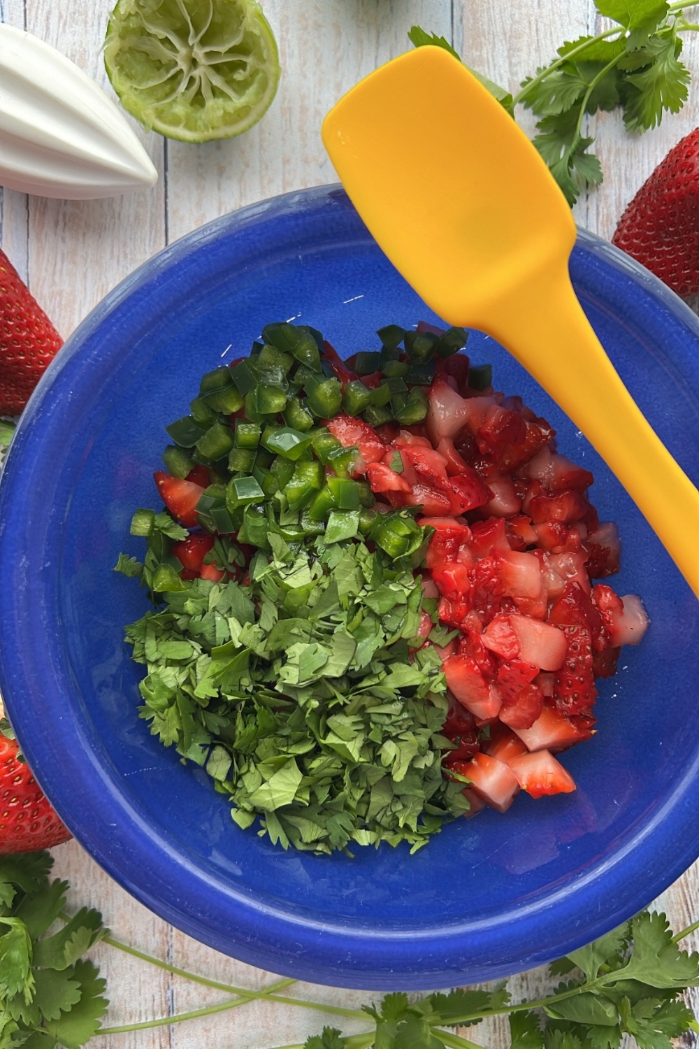 chopped strawberries, cilantro, and jalapeno in a blue bowl