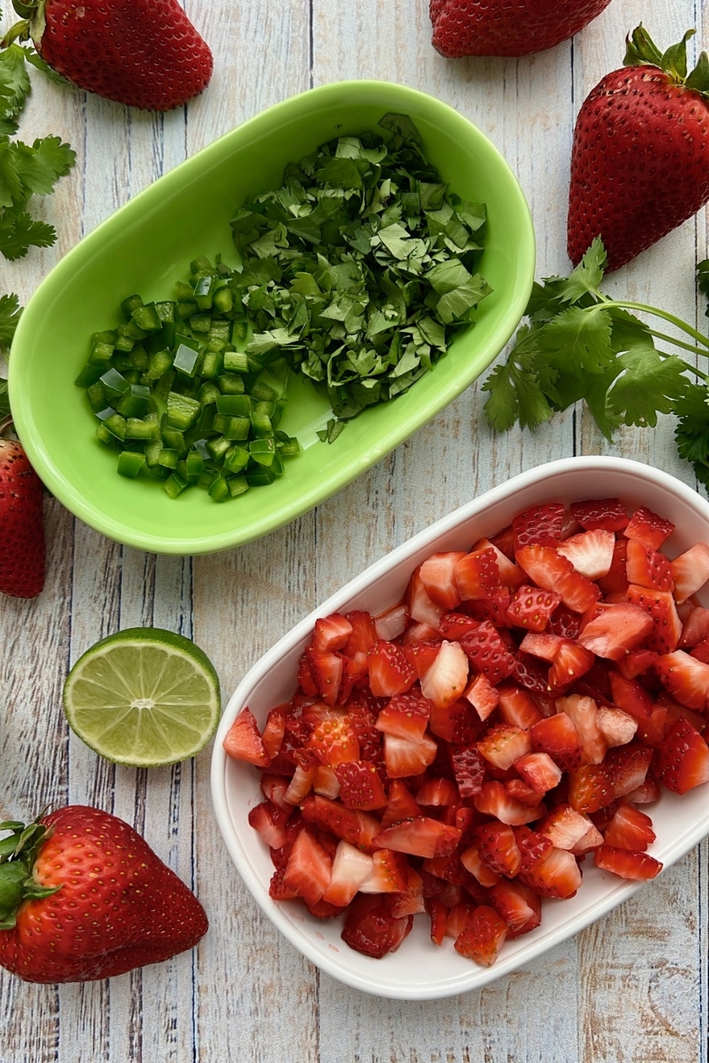 dish of diced strawberries and a dish of chopped cilantro and chopped jalapenos