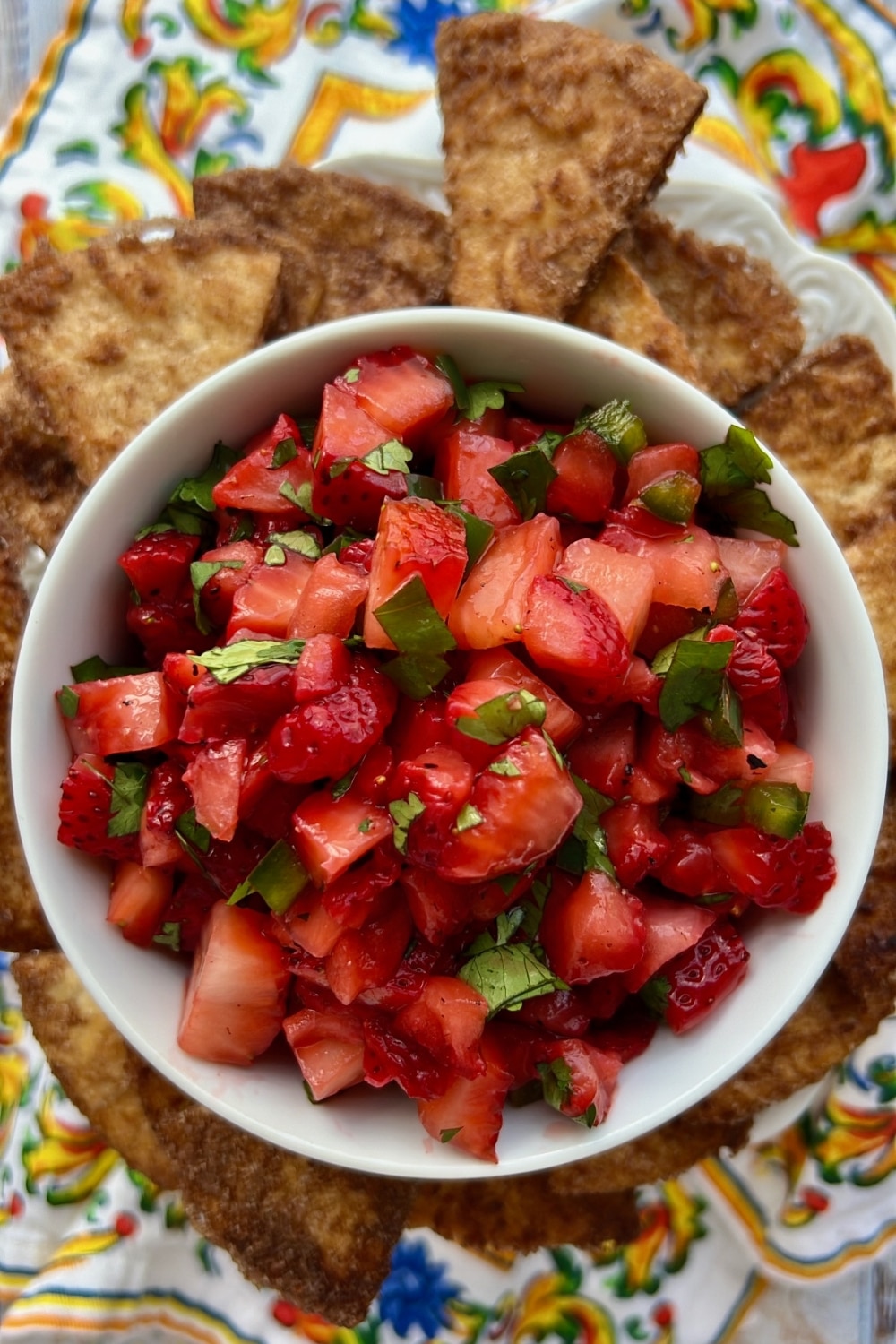 bowl of fresh strawberry salsa surrounded by cinnamon tortilla chips