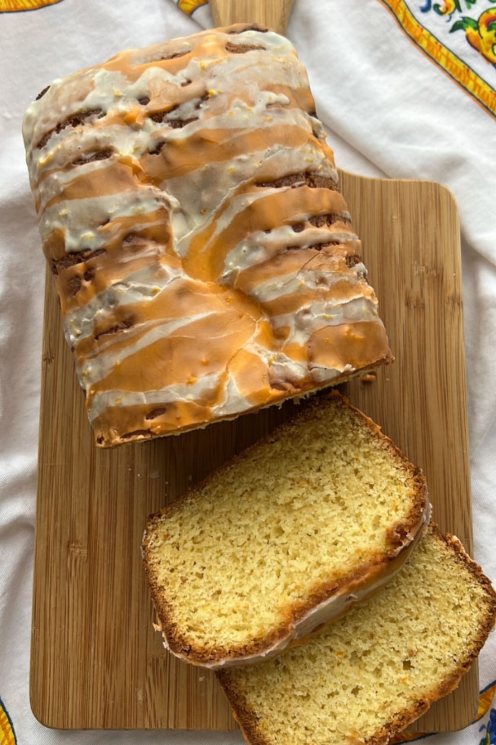 orange loaf cake on a cutting board with two slices laying down