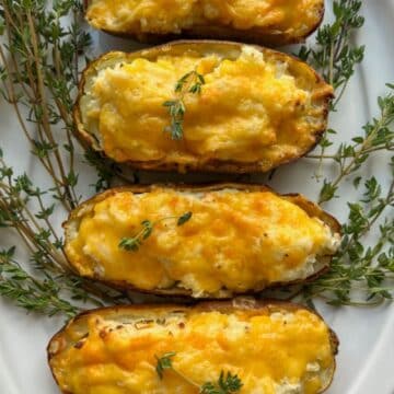platter of air fryer twice baked potatoes surrounded by fresh thyme sprigs