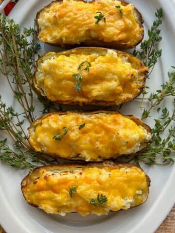 platter of air fryer twice baked potatoes surrounded by fresh thyme sprigs