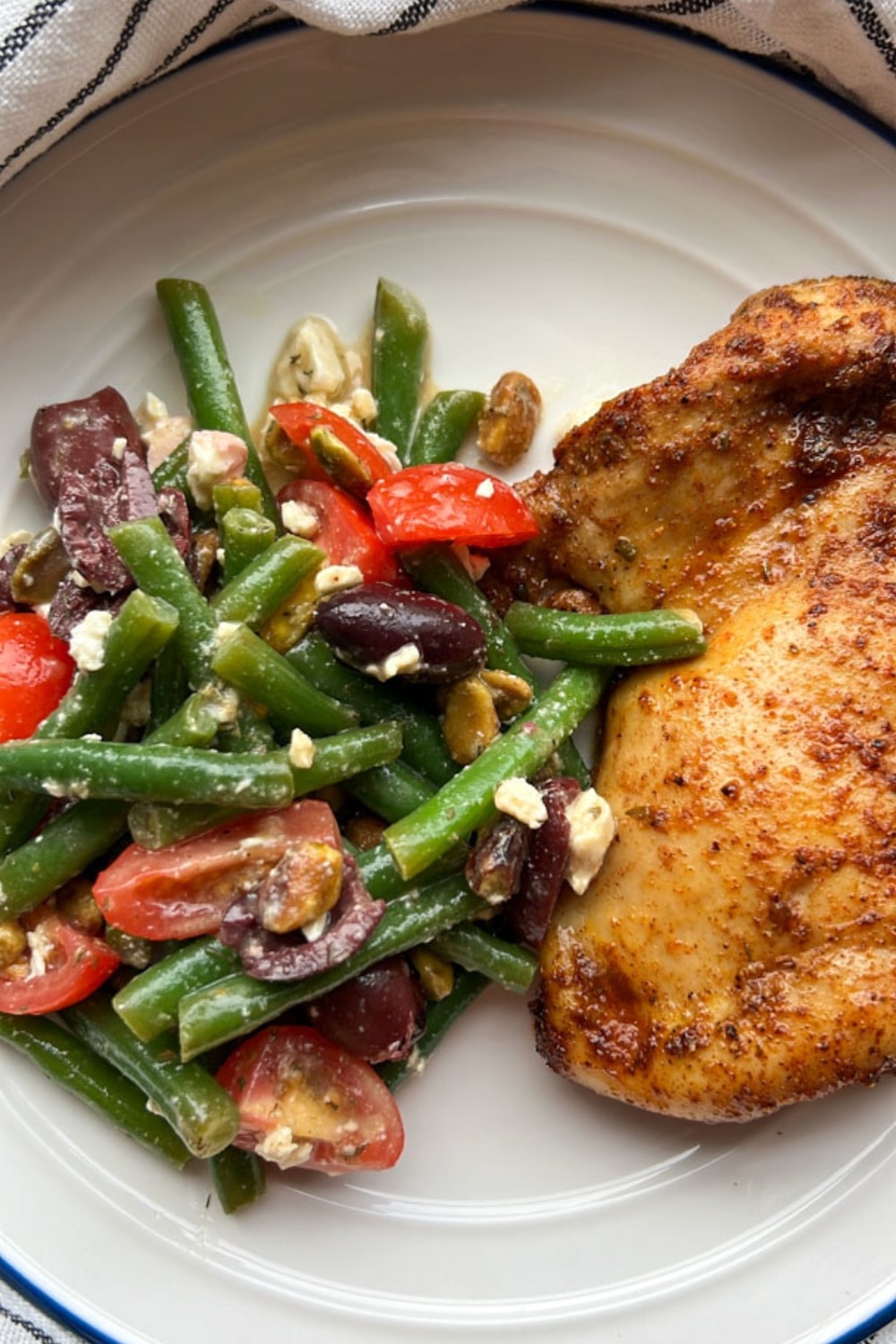 GREEK GREEN BEAN SALAD WITH ROASTED CHICKEN ON A WHTE PLATE