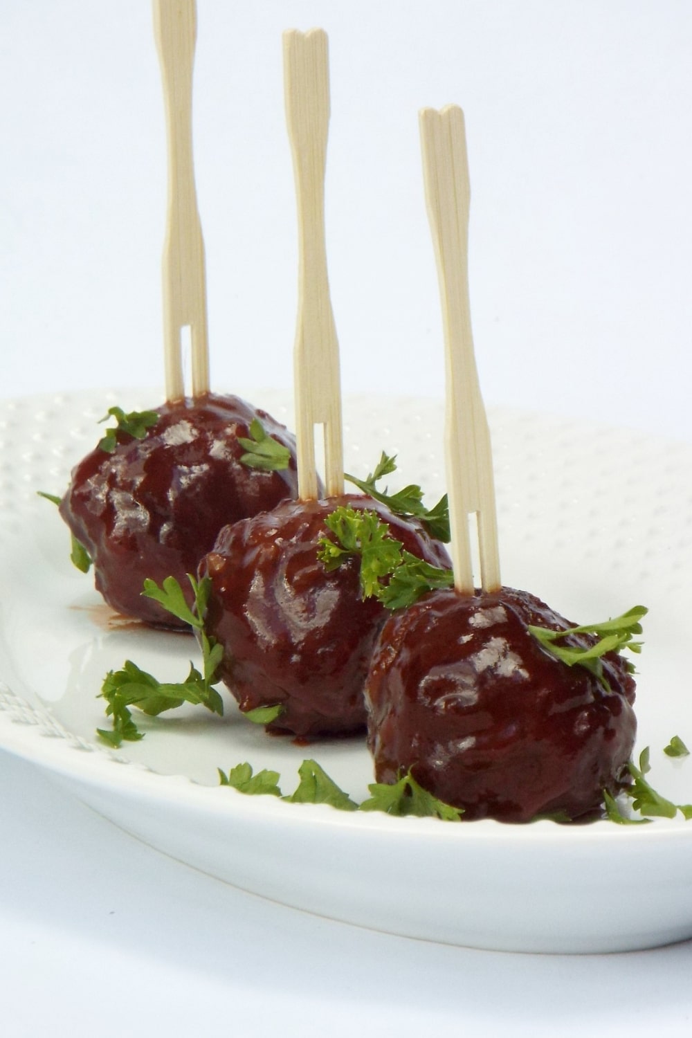 THREE MEATBALLS WITH SMALL FORKS SKEWERED IN THEM 