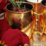 Merry mule cocktail in a mule glass garnished with rosemary and cranberries