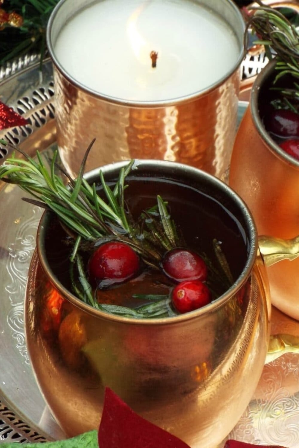 Merry mule cocktail in a mule glass garnished with rosemary and cranberries