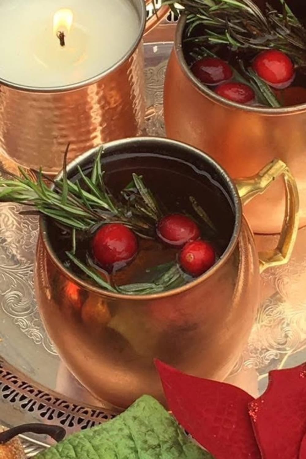 Merry mule cocktail in a mule glass garnished with rosemary and cranberries