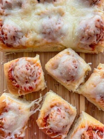 Sliced Hawaiian roll meatball sliders on a cutting board.