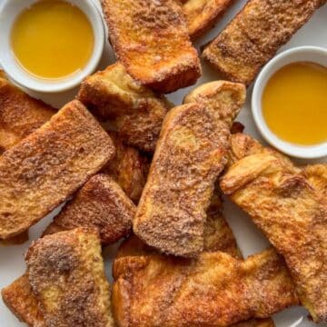 Air Fryer French Toast Sticks on a platter with syrup dipping sauce