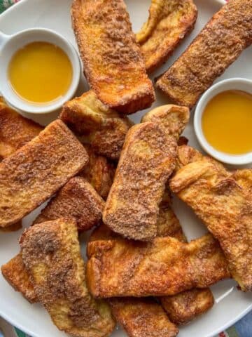 Air Fryer French Toast Sticks on a platter with syrup dipping sauce